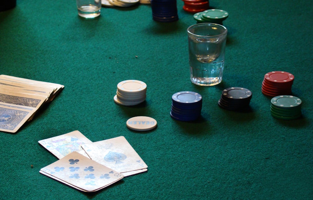 Kartu remi dan chip poker tersusun di atas meja hijau