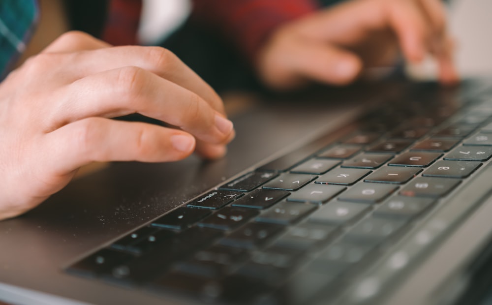 Tangan mengetik di atas laptop pada meja kerja